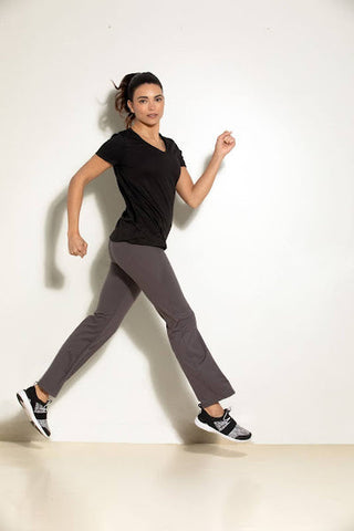 A woman wearing a black top and grey Felina leggings, while in a jogging pose and looking at the camera.
