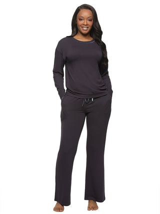Anala - A woman wearing a navy bulue 2-piece lounge set with a long-sleeved pullover and pants, both with velvet trim, standing with hands in pockets.