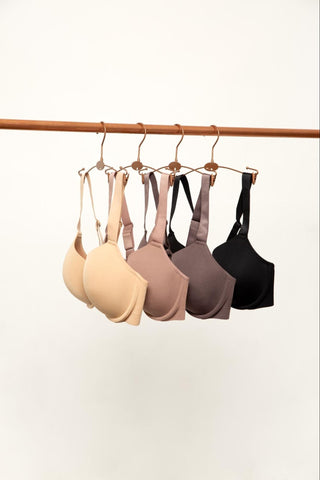 Four Utopia Bras are hanging on a copper-colored rod.