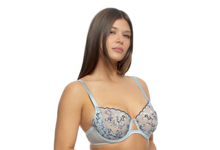 A person with brown hair is wearing a light-blue, floral, and lacy bra while looking at the camera.