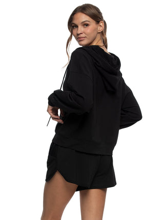 Woman wearing a black hoodie and shorts on a white background back view
