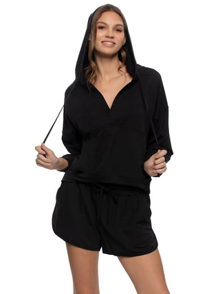 Woman wearing a black hoodie and shorts set on a white background