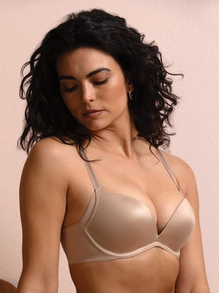 Woman wearing a beige bra against a pink background Kyra