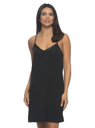 A woman wearing a pnavy blue satin chemise slip dress with thin adjustable straps and a v-neckline.