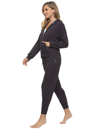 A female model wearing a navy blue 2-piece lounge set with a zip-up hoodie and matching joggers side view walking with hand in jacket pocket