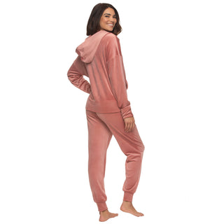 Woman wearing a pink velvet zip-up hoodie and matching pants on a white background