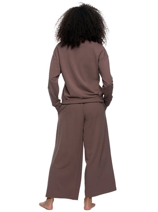 Woman wearing a brown outfit with wide-leg pants on a white background