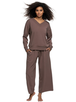 Woman wearing a brown sweatshirt and pants set on a white background